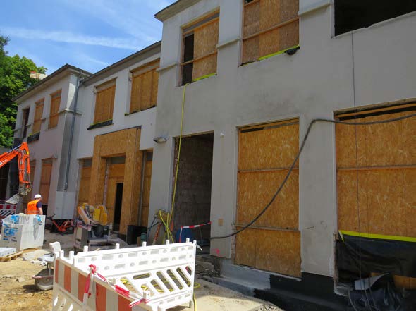 Die eingerüstete Fassade des Altbaus mit verschalten Fenstern